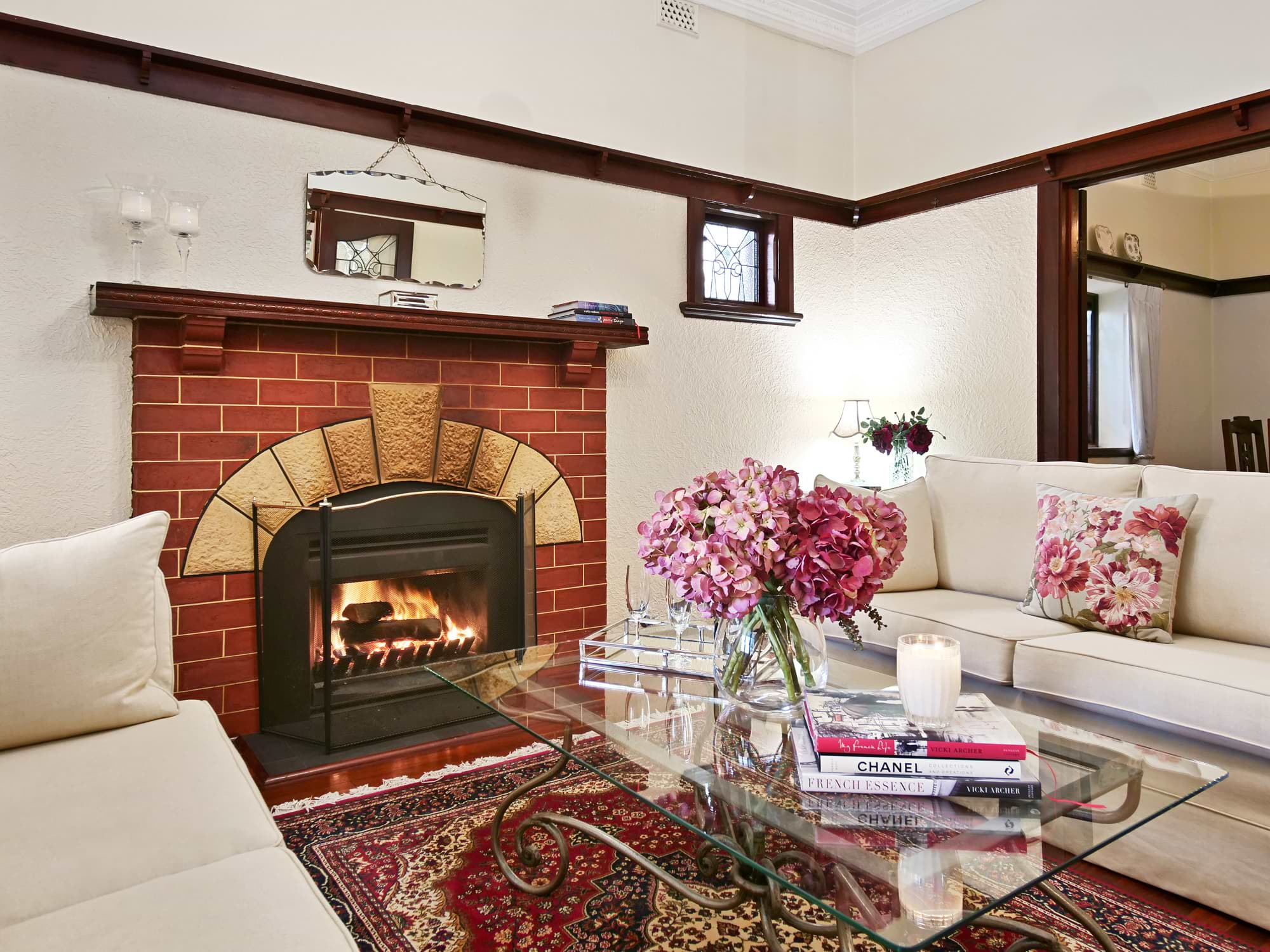 Living room of Kensington, Perth property with fireplace and flowers on glass coffee table