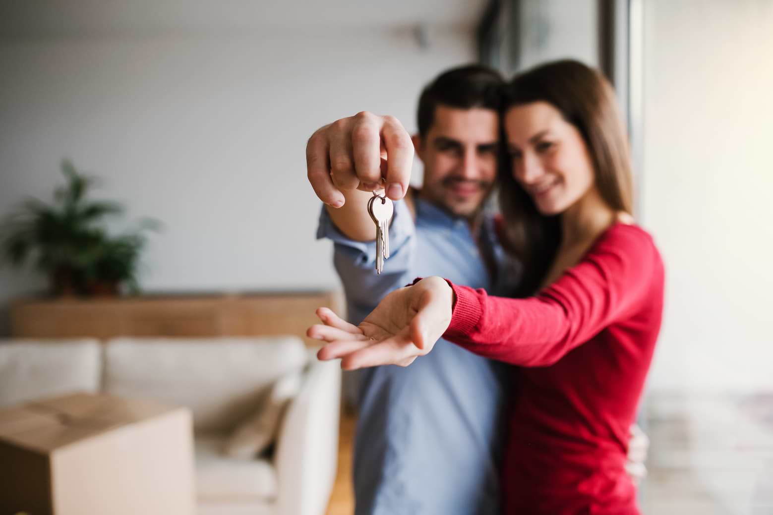 a young couple holding a pair of house keys